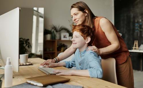 teen studying at a computer with mother